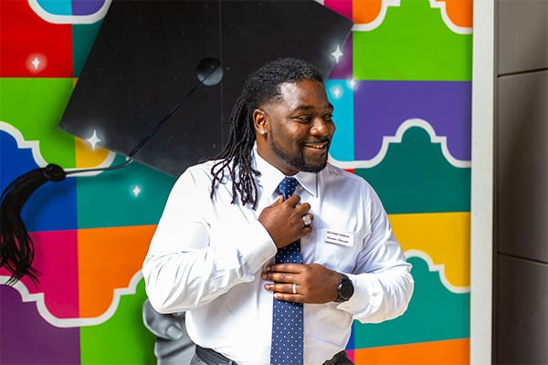 Richard Jordan posing in front a street painting mural of alamo colleges district logos