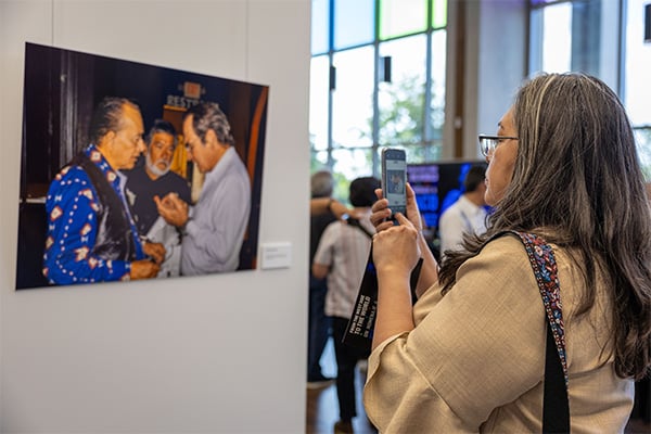 A woman takes a photo of one of the "Flaco" Jimenez photos on display.