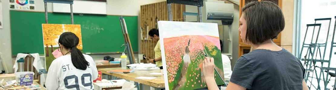 Two students painting on a canvas